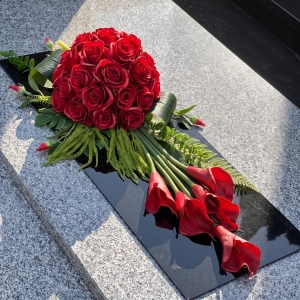 Wiązanka na cmentarz czerwona z callami, na czarnej płycie pleksi, na pomniku