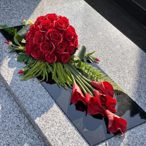 Wiązanka na cmentarz czerwona z callami, na czarnej płycie pleksi, na pomniku