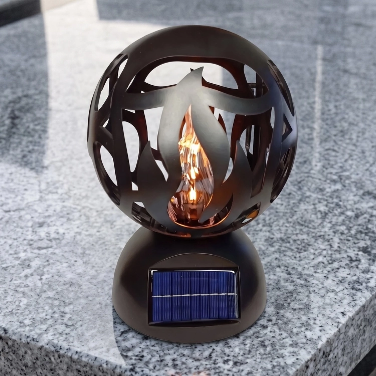 Znicz solarny LED czarny w formie ażurowej kuli z motywem płomienia, na granitowym nagrobku